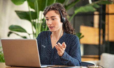 Customer service agent wearing a headset helping a client on a laptop, representing modern queue and support management