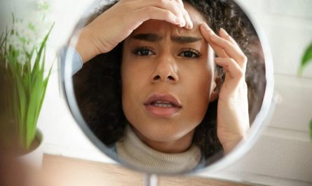 Young woman in the UAE checking acne breakouts on her forehead in a mirror